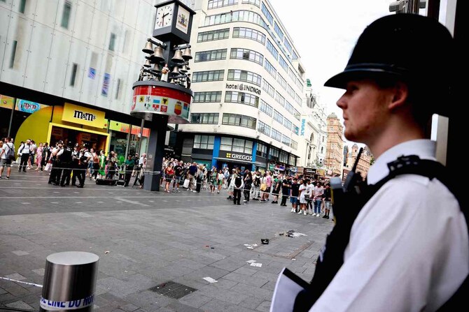 A police officer stands by a cordoned off area in Leicester square, London after a woman and a girl were hospitalised.