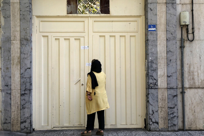 A woman reads the Iranian police closure notice on the gate of a language institute certified by German embassy, in Tehran, Iran