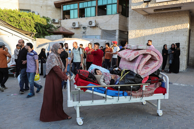 Patients fearing an Israeli ground operation are assisted to flee Al-Aqsa Martyrs hospital. (Reuters)