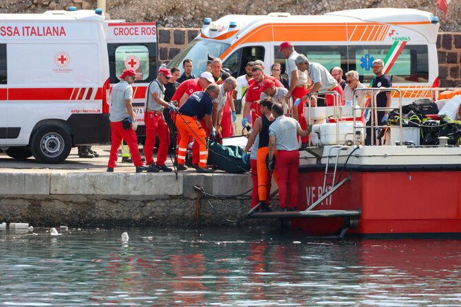 Italian firefighters and health workers carry a body bag with a victim after a sailboat sank off the coast of Porticello.