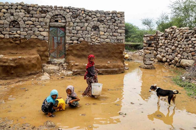 Children fill up a jerrycan from a water puddle left by recent heavy flooding in the Hays region, south of Hodeidah province.