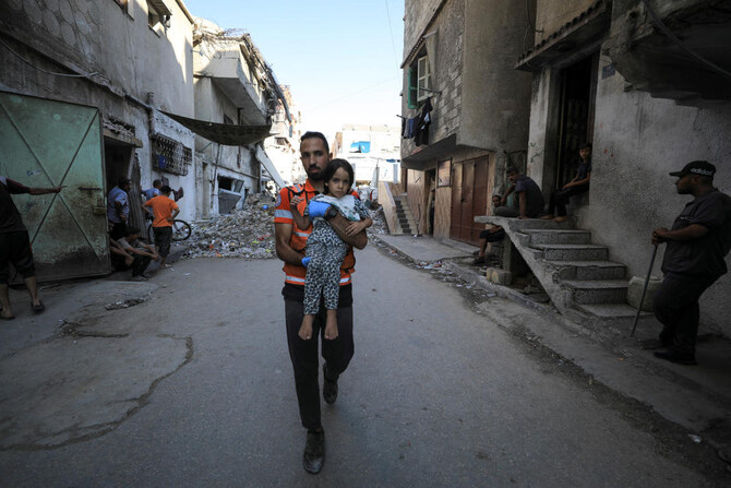 A civil defence worker carries a girl at a school site, which was sheltering displaced people,after it was hit by Israeli strike