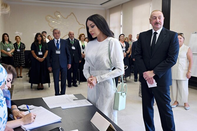 Azerbaijani President Ilham Aliyev, right, and his wife and Vice President Mehriban Aliyeva line up to collect their ballots.