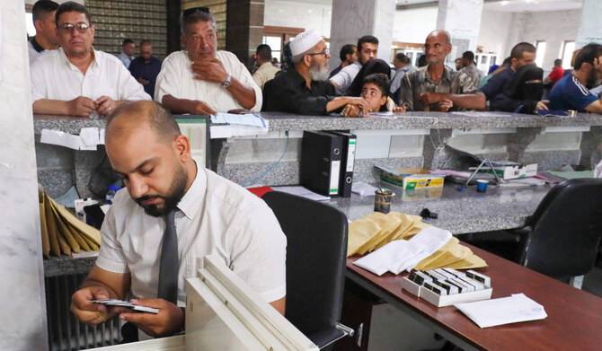 A bank teller looks for a customer's debit card at a bank in Libya's western coastal city of Misrata on August 25, 2024. (AFP)