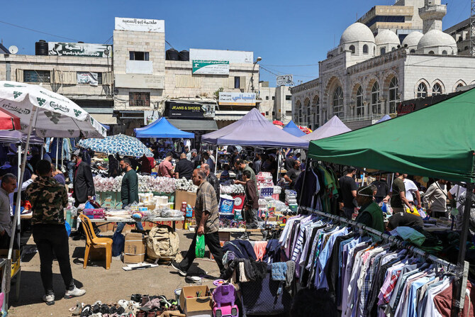 Palestinians shop at a market in Ramallah, in the occupied West Bank on April 19, 2024. (AFP)