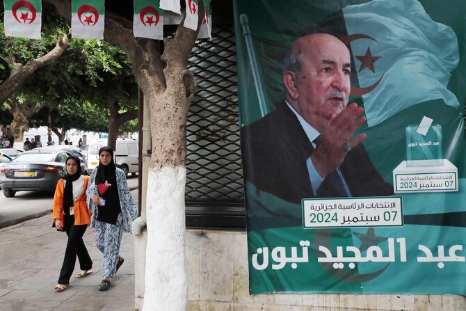 People walk past posters of Algeria’s President Abdelmajid Tebboune outside an election campaign headquarters in Algiers.