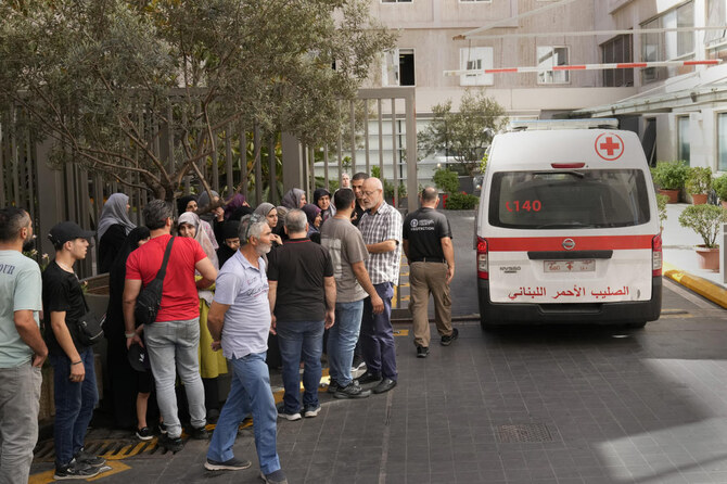 Lebanese Red Cross ambulance passes next of the families of victims who were injured on Monday by their exploding handheld pager