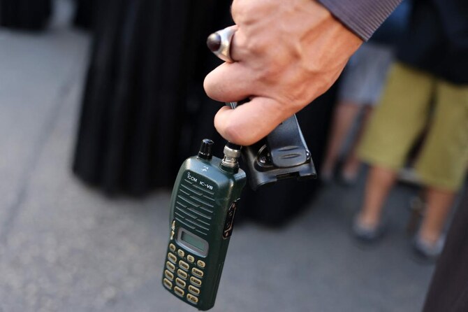 A man holds a walkie talkie device after he removed the battery.