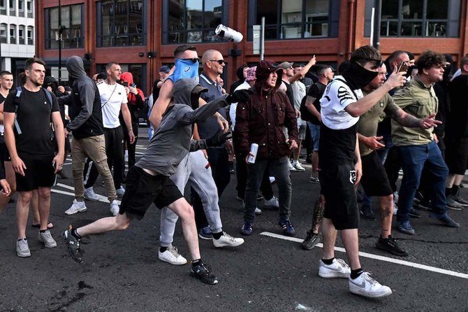 A masked protester throws a can of beer towards riot police in Bristol during riots last week. (AFP)