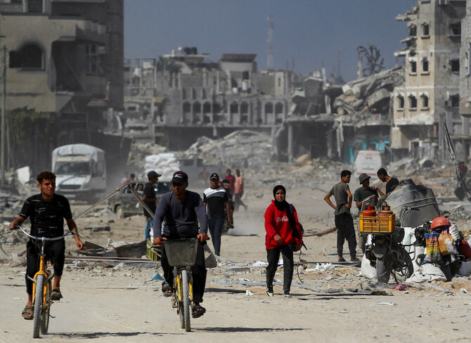 Palestinians pass by the damage after Israeli forces withdrew from Khan Yunis. (Reuters)