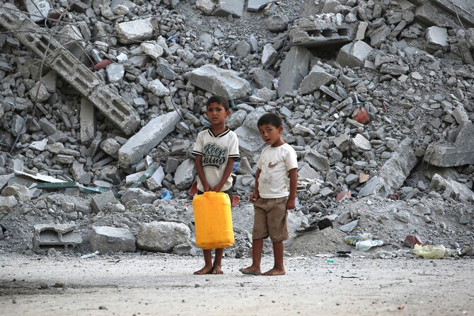 Palestinian boys stand with a water container near a pile of debris in Nuseirat in the central Gaza Strip. (AFP)